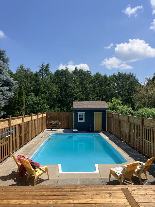 Backyard pool area with wood deck edge and privacy fence