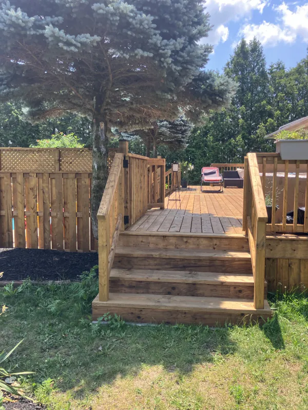 Wood deck stairs, railing, and backyard seating area